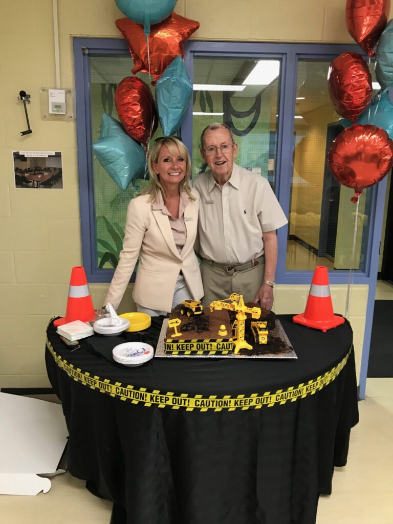 Executive Director, Brigitte Tschinkel, and Jerry Coughlan smiling in front of a cake that displays the breaking of ground in Ajax for Grandview Kids new facility.